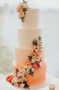 a three tiered wedding cake with flowers on the top and bottom, sitting on a table