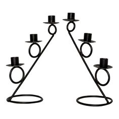 a set of four black candlesticks with one candle in the middle and two on each side