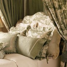 a bed covered in green and white pillows