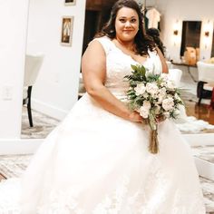 a woman in a white dress holding a bouquet and posing for the camera on her wedding day