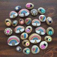 some rocks with designs on them sitting on a wooden table and one has a rainbow painted on it