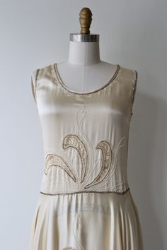 "Antique 1920s cream silk charmeuse dress with cream lace filled cutouts outlined with pearls, classic 1920s simple shape and drop waist and side metal hook and eye closures. [m e a s u r e m e n t s] fits like: extra small/small bust: best fit up to 32.5\" waist: best fit up to 26\" hip: free length: 42\" [i n f o] brand/maker: n/a fabric content: silk condition: excellent (very faint underarm discoloration), and a break in the lace on the skirt, see close up. to ensure a good fit, please read 1920s Embellished Sleeveless Flapper Dress, 1920s Style Sleeveless Flapper Dress For Wedding, 1920s Sleeveless Flapper Wedding Dress, Art Deco Sleeveless Wedding Dress, Vintage Sleeveless Flapper Wedding Dress, Vintage Sleeveless Flapper Dress For Wedding, 1920s Sleeveless Wedding Flapper Dress, Silk Gatsby Style Wedding Dress, Silk 1920s Evening Flapper Dress