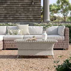 a white couch sitting on top of a gravel covered ground next to a wooden building