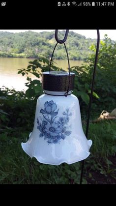 a bell hanging from a pole next to a body of water with trees in the background