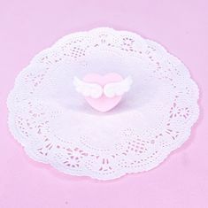 a white doily with a pink heart and angel wings sitting on top of it