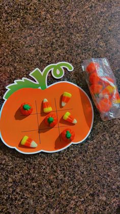 candy candies are arranged on an orange pumpkin shaped cutout next to a bag of candy