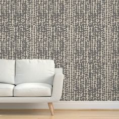 a white couch sitting in front of a wall with grey and white designs on it