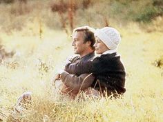 a man and woman sitting in tall grass