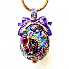 This is a high-quality, 24k gold plated, 925 sterling silver handmade magnificent egg-shaped pendant inspired by and designed in a traditional Faberge style. On the front of the pendant is the design with traditional multicolor cloisonne enameled filigree ornaments and 4 different sizes from 2mm to almost 4mm high dome genuine garnet cabochons.  On both sides of the pendant are also lines of crystals.  The bail with crystals is above the purple enameled bow, and on the bottom of the pendant is a 2mm garnet cabochon. The pendant is approximately 1.1" in height and comes with a 24-inch snake chain. A jewelry box is included.   I am a professional jewelry designer, who graduated from Saint Petersburg's Art and Design Academy. Immigrating to the USA, I brought back Faberge's style and traditio Enamel Art, Faberge Egg, Art Deco Necklace, Professional Jewelry, Schmuck Design, Snake Chain, Handmade Silver, Garnet, Jewelry Necklace Pendant