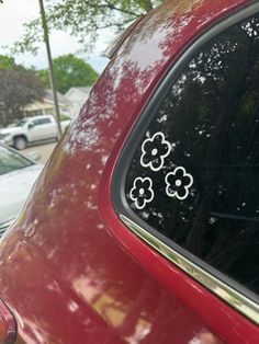 the back window of a red car with four flowers on it's decal