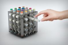 a hand is pointing at an object made out of plastic tubes and other colored objects