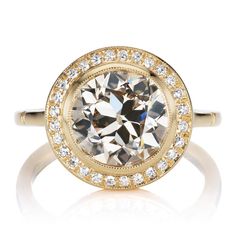 a ring with an oval shaped diamond surrounded by smaller round diamonds in yellow gold and white gold