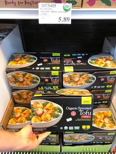 a person pointing at some food in a store display case with other items on the shelf