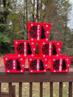 red boxes with black and white designs on them sitting on a wooden bench in front of trees