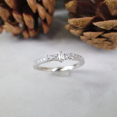 a diamond ring sitting on top of a table next to pine cones