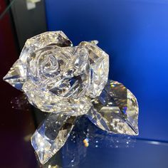 a crystal rose sitting on top of a table next to a blue wall in the background