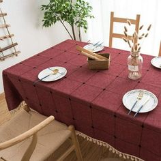 the table is set with plates and silverware on it, near a potted plant