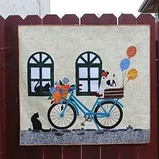 a painting on the side of a building with a bike and cat in front of it