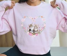 Introducing our whimsically Kitten Heart Sweatshirt - a true nod to the vintage 90s era with a delightful touch of French charm! Adorned with adorable kittens in a 90s portrait style, this sweater is your ticket to cuteness overload. Whether you're a feline enthusiast or simply appreciate the whimsy of vintage-inspired fashion, this sweater is your purr-fect companion for adding a touch of playfulness to your wardrobe. Get ready to make a statement that's both timeless and utterly meow-gical! This sweatshirt also makes a wonderful gift for cat moms and cat lovers alike. The floral heart design makes it especially purr-fect for Valentine's Day! * 50% cotton, 50% polyester * Pre-shrunk * Classic fit, size up for oversized fit * 1x1 athletic rib knit collar with spandex * Air-jet spun yarn wi Coquette Kitten, Coquette Cat, Cute Cottagecore, Cat Vintage, Adorable Kittens, Cottagecore Coquette, Sweatshirt Trendy, 90s Era, Heart Sweatshirt