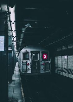 a subway train pulling into the station with its lights on and no people around it