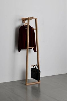 a coat rack with a sweater hanging on it and a purse in the foreground