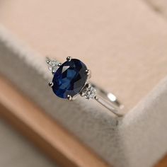 a close up of a ring with a blue stone on it in a white box