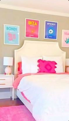 a white bed sitting in a bedroom next to a pink rug and two pictures on the wall