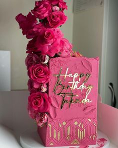 a pink birthday cake with flowers on top