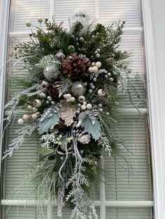 a christmas wreath hanging on the front door with pine cones, berries and evergreens