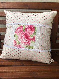 a pillow with pink flowers on it sitting on a bench