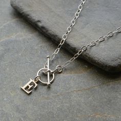 "This sterling silver necklace features a sterling silver Initial charm and has a T bar clasp for front fastening It is made from flat oval sterling silver trace chain The sterling silver initial charm measures approx 9 mm depending on the letter chosen, The t-bar measures 18 mm with the ring having a 10 mm outside diameter Available in  a choice of 14\", 15\", 16, 18  or 20 inch sterling silver chain. A Lovely everyday wear necklace. Lovely gift for a loved one. The necklace will arrive in a gi Personalized Silver Toggle Necklace Gift, Engraved Silver Toggle Necklace As Gift, Classic Oval Link Toggle Necklace As Gift, Classic Oval Link Toggle Necklace Ideal For Gifts, Classic Sterling Silver Toggle Necklace, Minimalist Sterling Silver Toggle Necklace As Gift, Oval Link Toggle Necklace As Gift, Minimalist Sterling Silver Toggle Necklace, Silver Oval Link Charm Necklace For Everyday