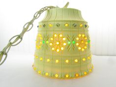 a green lamp with yellow lights on it sitting on a white table next to a chain