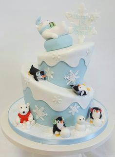 a three tiered cake decorated with penguins and snowflakes