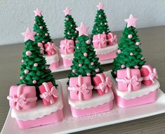 small pink and green christmas trees are on a white platter with bows, ribbons and bows around them