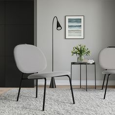 two white chairs sitting next to each other on top of a rug