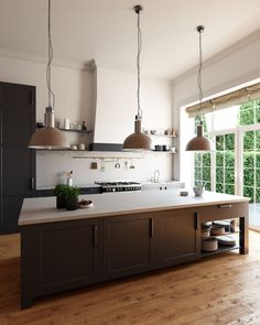 a kitchen with an island and two pendant lights hanging over the stove top in front of a large window