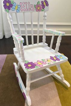 a child's rocking chair with flowers on the seat and name written on it