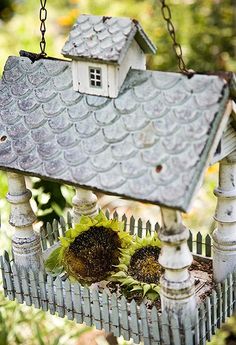 a birdhouse with sunflowers in the foreground