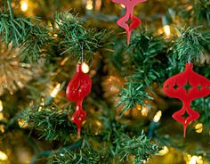 red ornaments are hanging from a christmas tree