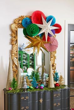 an ornate dresser decorated with christmas decorations and paper stars on it's top, in front of a mirror