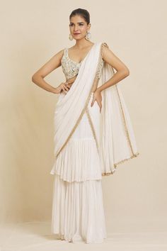 Ivory pre-stitched stripe pattern ruffle saree, accentuated with an embroidered border and pearl embellishments. Paired with a hand embroidered blouse in mirror and pearl work. - Aza Fashions White Sleeveless Blouse For Diwali, White Sleeveless Blouse Piece For Reception, White Sleeveless Blouse For Reception, White Pre-draped Saree With Ruffles In Traditional Drape, White Georgette Pre-draped Saree, White Pre-draped Saree With Ruffles, Traditional Drape Pre-draped Saree In Off White, White Sleeveless Blouse Piece For Wedding, Sleeveless White Blouse Piece For Wedding