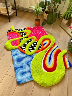 the colorful rugs are on the wooden floor next to plants and potted plants