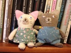 two stuffed animals sitting on top of a wooden shelf next to bookshelf filled with books