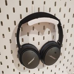 headphones are hanging on the wall in front of white perfored background with holes