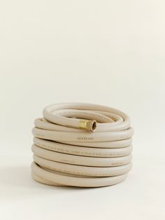 a white hose with a gold fitting on the end is shown in front of a white background