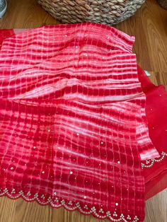 Aalna exclusive- a 100% pure organza completely hand dyed in the prettiest baby pink shade with tie-dye bandhej and shibori craft. The bandhej is done in the body and the shibori is in the palla. Both are done completely by hand. It is NOT a print. The combination of bright red and cream is stunning. After the dyeing, intricate scallop border and beautiful embroidery is done in the border as well as in the body in the bandhej butas. Micro size mirror is also hand stitched throughout the saree. I Pink Organza Dupatta For Transitional Season, Transitional Pink Organza Dupatta, Festive Red Dupatta With Batik Print, Red Dupatta For Summer Parties, Pink Bandhani Print Sets For Summer, Pink Bandhani Print Summer Sets, Summer Bandhani Print Pink Sets, Pink Georgette Dupatta For Summer, Traditional Summer Organza Dupatta