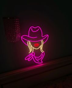 a neon sign with a woman's face wearing a hat and holding her hands up