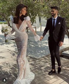 a man and woman in formal wear holding hands