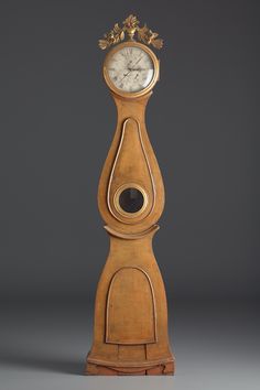 an old wooden grandfather clock sitting on top of a table next to a gray wall