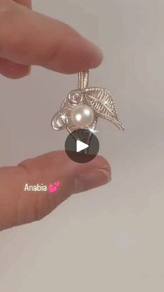 a person is holding a silver bird charm